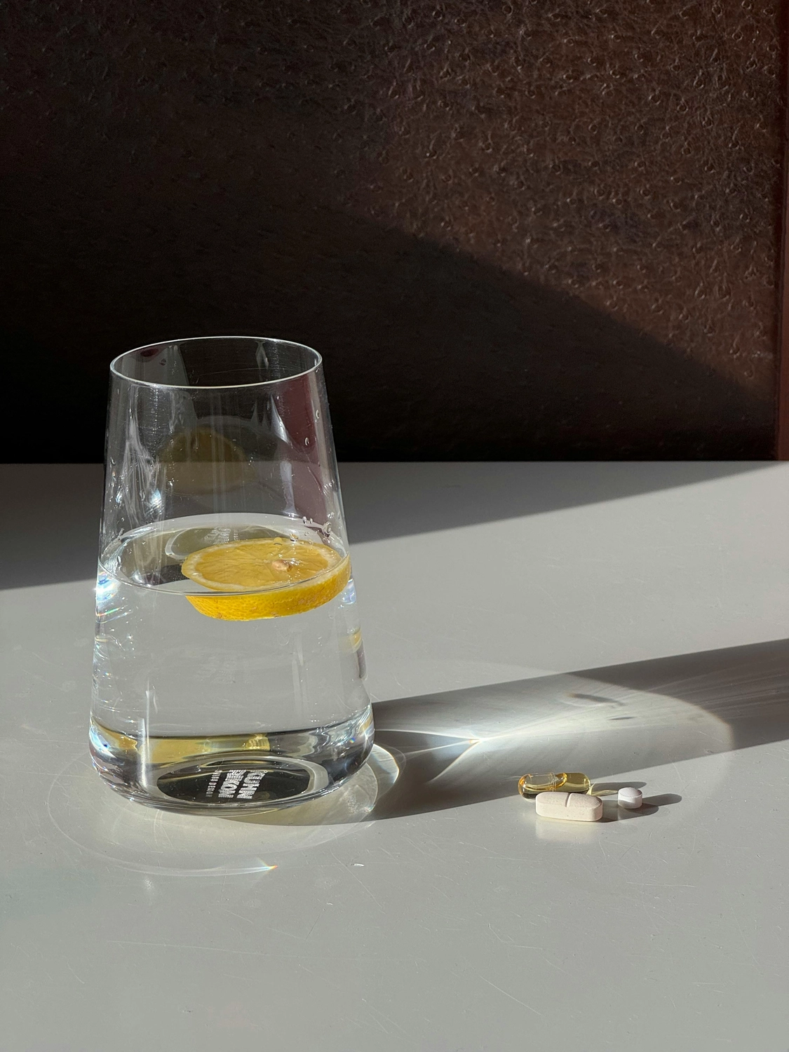 Besser Pflege Ambulant - Ambulanter Pflegedienst - Zitronenscheibe im Wasserglas und Tabletten daneben